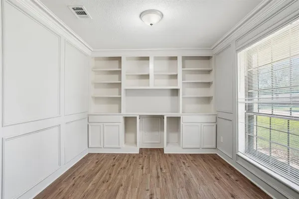 a view of an empty room with a window and wooden floor