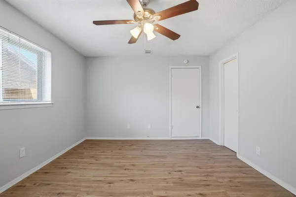 a view of an empty room with window and chandelier fan