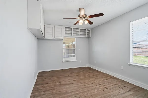 a view of empty room with wooden floor and fan
