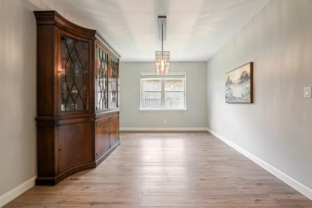 an empty room with wooden floor cabinet and windows