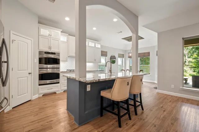 a kitchen with stainless steel appliances a dining table chairs and wooden floor