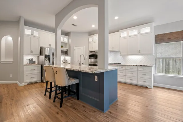 a kitchen with stainless steel appliances kitchen island granite countertop a table chairs sink refrigerator and cabinets