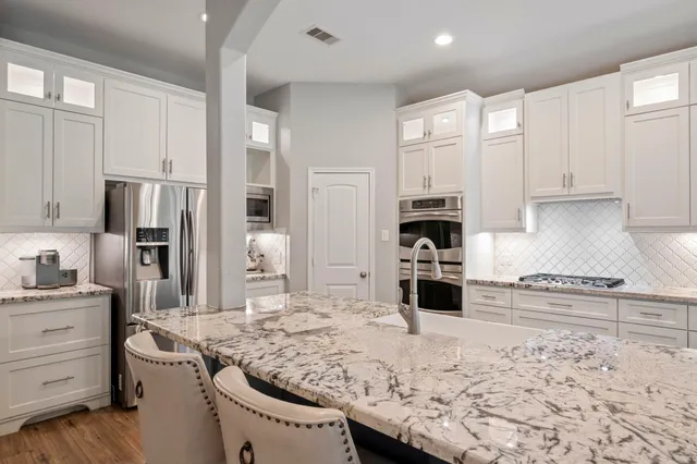 a kitchen with stainless steel appliances granite countertop a stove refrigerator and cabinets
