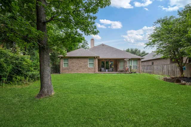 a view of a yard in front of a house with large tree