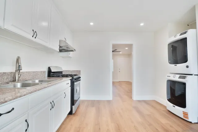 a kitchen with stainless steel appliances granite countertop a sink and a stove top oven with wooden floor