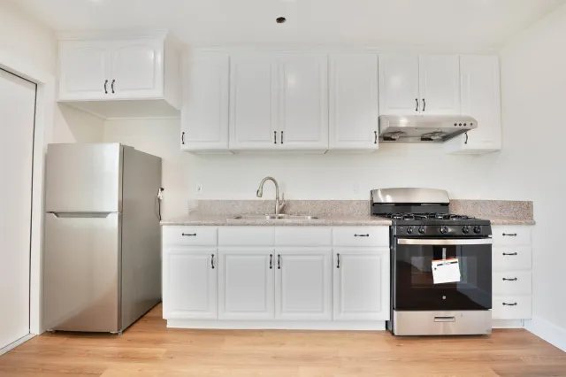 a kitchen with stainless steel appliances granite countertop a stove a refrigerator and a white cabinets
