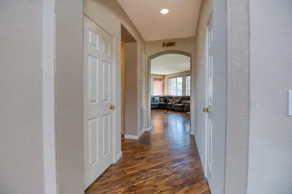 a view of a hallway view with wooden floor and a living room