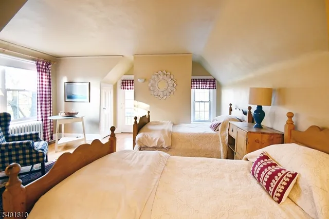 a bedroom with two beds and a large mirror next to a window