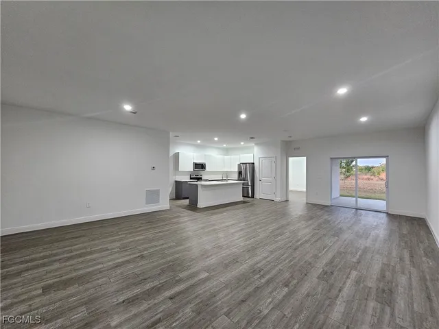 a view of an empty room with wooden floor and windows