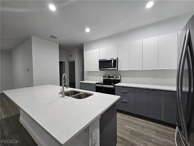 a kitchen with sink a microwave and cabinets