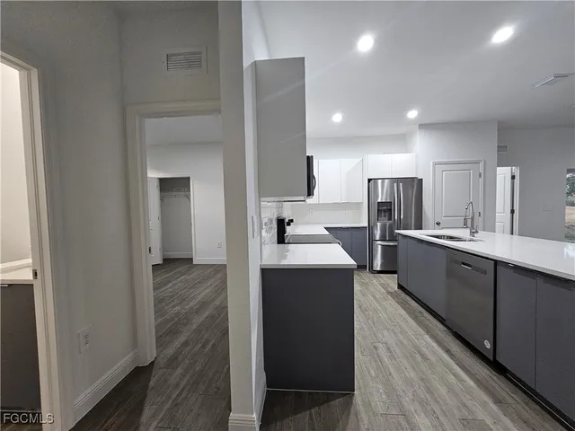 a large kitchen with a counter top space a sink stainless steel appliances and cabinets