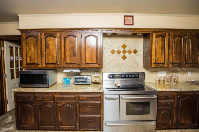 a kitchen with stainless steel appliances granite countertop a refrigerator a stove and a sink with cabinets