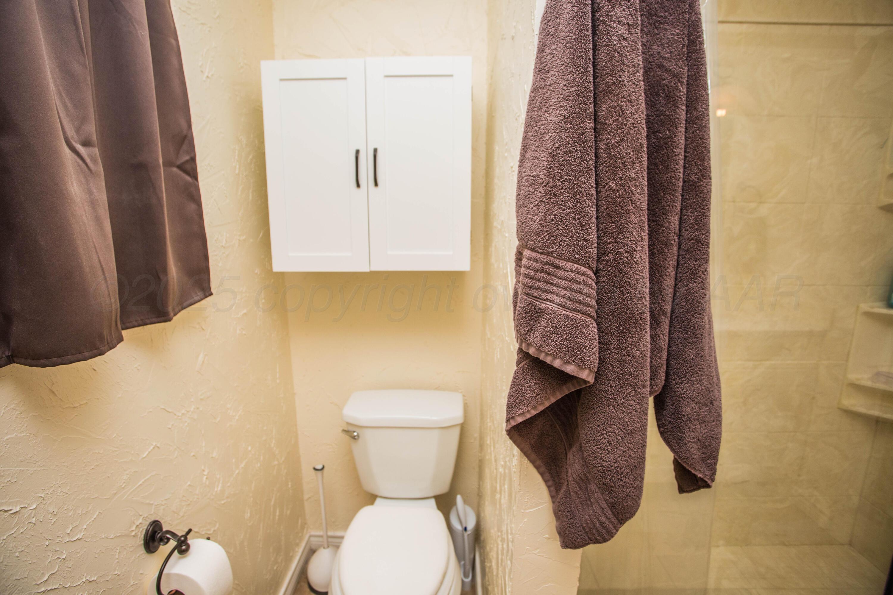 402 Northwest 6th Street Tulia, TX 79088 - Photo 30 of 59 a bathroom with a toilet and a shower curtain