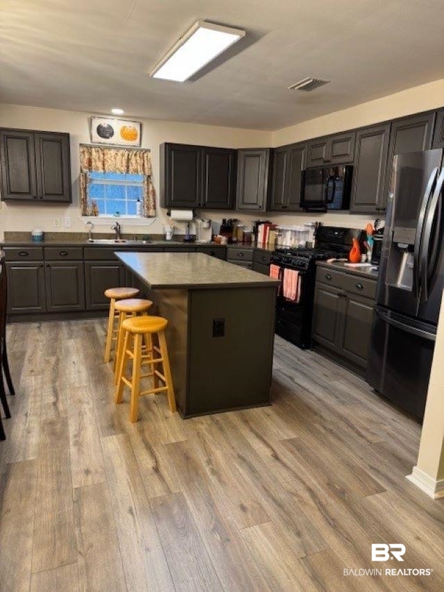 8100 Coden Belt Road West Coden, AL 36523 - Photo 5 of 12 Kitchen featuring a breakfast bar, light hardwood / wood-style floors, a kitchen island, and black appliances