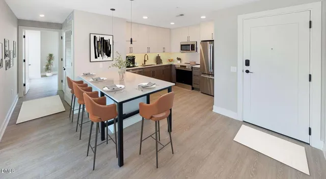 a kitchen with kitchen island a stove a sink a dining table and chairs