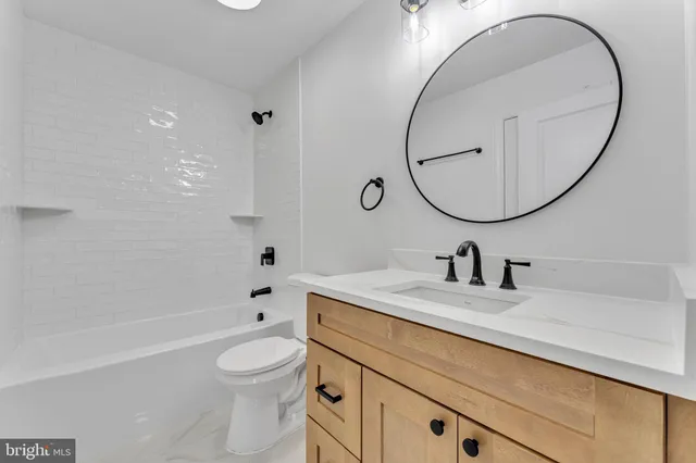 a bathroom with a granite countertop toilet a sink and a mirror