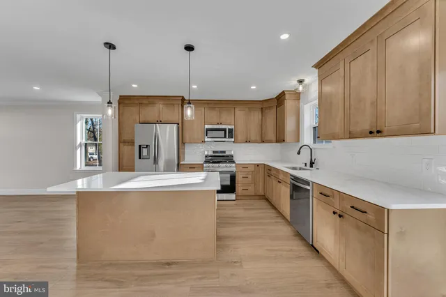 a large kitchen with stainless steel appliances granite countertop a stove a sink a refrigerator and a refrigerator