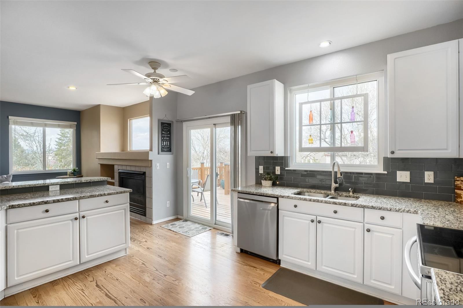 25 Estack Place Highlands Ranch, CO 80126 - Photo 10 of 28 a kitchen with a sink dishwasher a stove and white cabinets with wooden floor