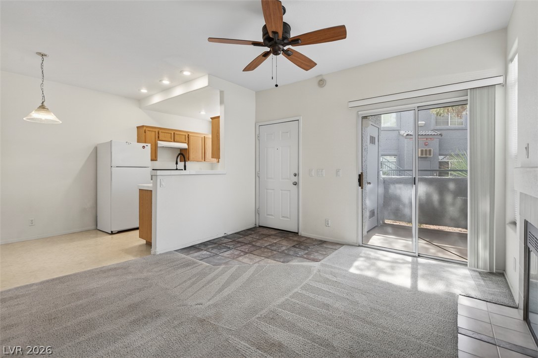 2201 Ramsgate Drive, Unit 1011 Henderson, NV 89074 - Photo 9 of 40 A living space seamlessly connects to a compact kitchen area, bathed in natural illumination from the sliding glass door.