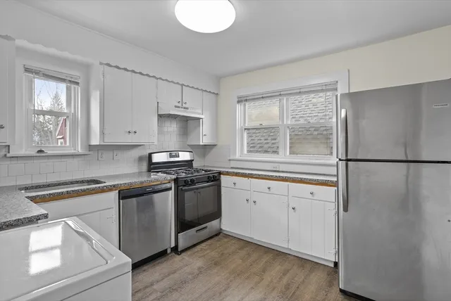 a kitchen with granite countertop white cabinets white stainless steel appliances and a sink