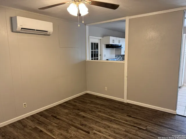 a view of empty room with wooden floor and fan
