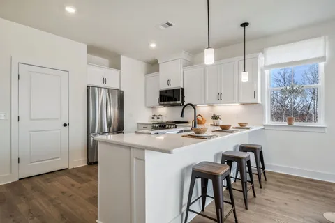 a kitchen with stainless steel appliances granite countertop a stove a refrigerator a sink a stove a dining table and chairs