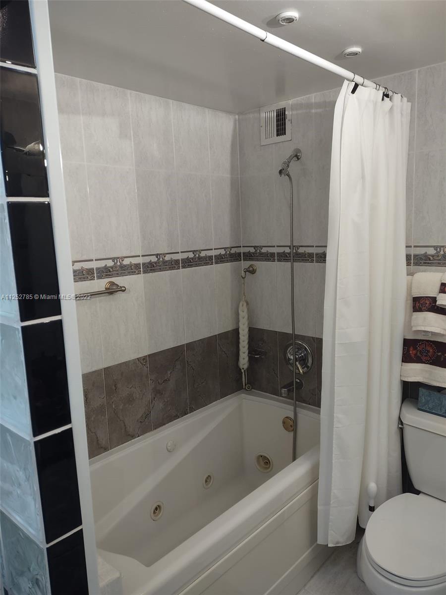 4747 Collins Avenue, Unit 107 Miami Beach, FL 33140 - Photo 14 of 15 a bathroom with a bathtub a toilet and a shower