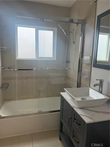 a bathroom with a granite countertop sink a mirror and a bathtub
