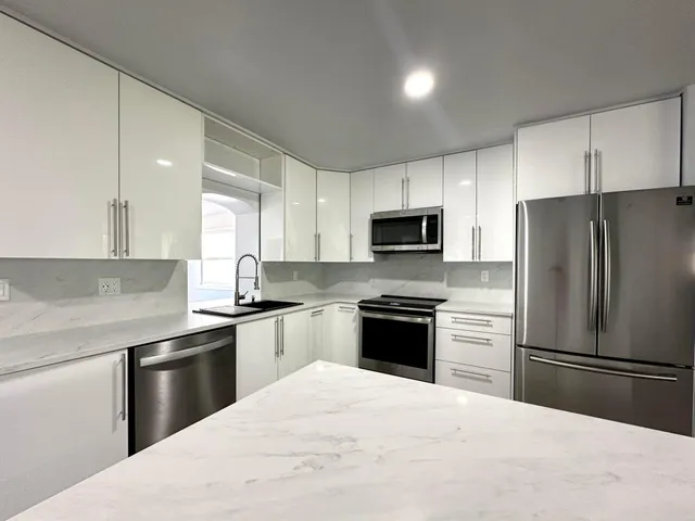 a kitchen with granite countertop a refrigerator stove and microwave