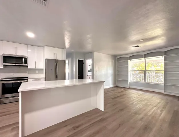 a large kitchen with stainless steel appliances a large window and a refrigerator