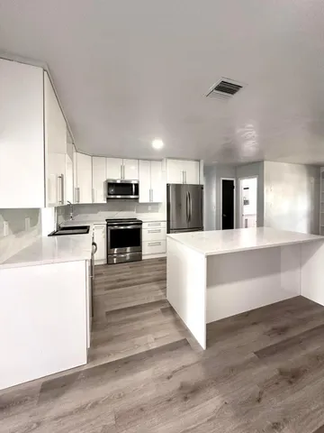 a large kitchen with stainless steel appliances kitchen island a large counter top and a stove top oven