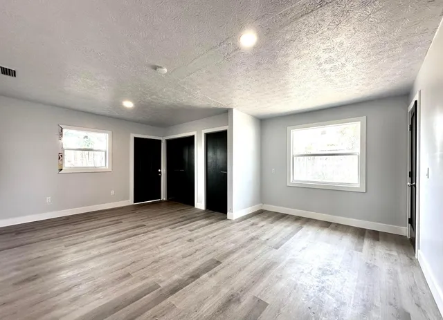 an empty room with wooden floor and windows