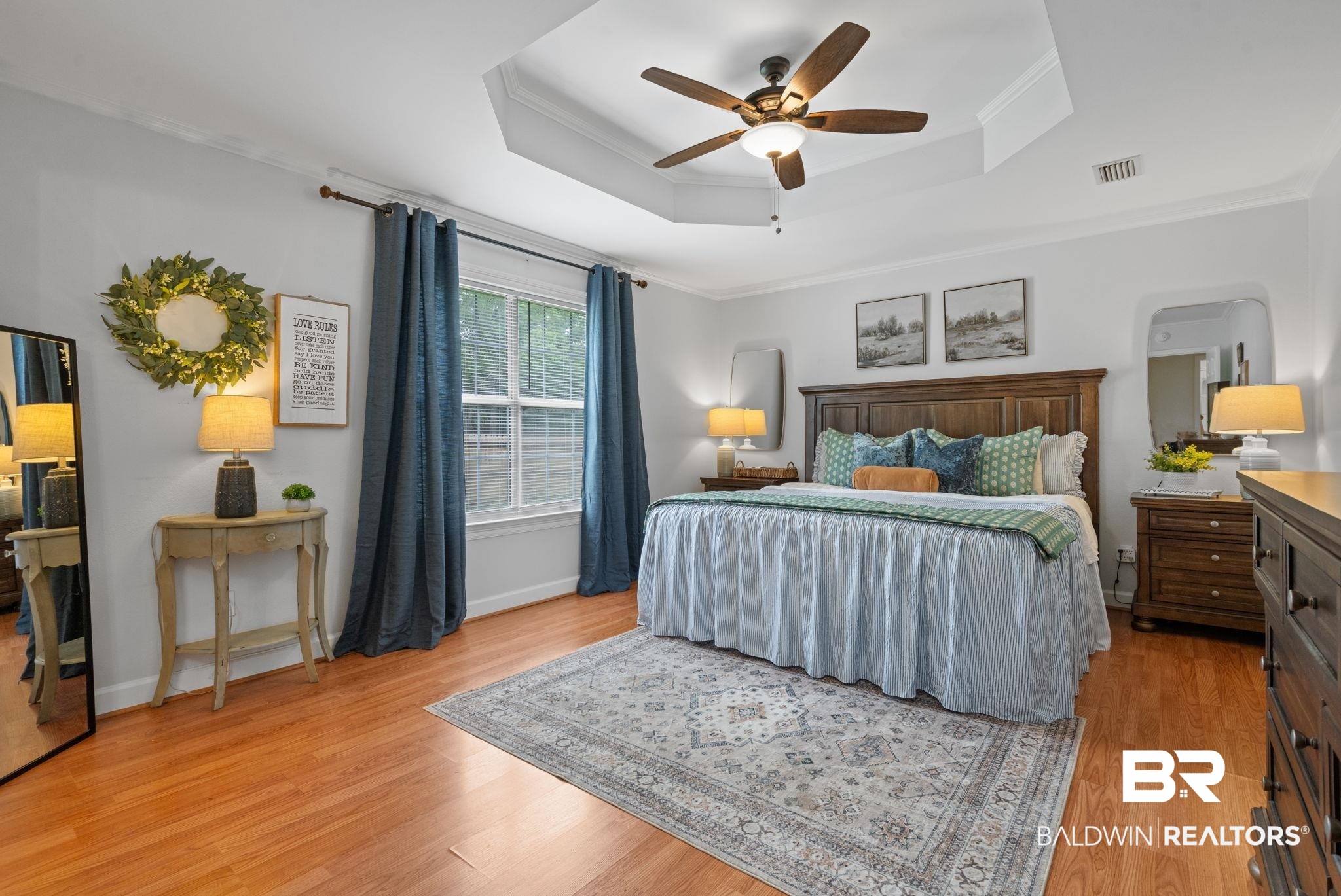 5936 Lundy Road Theodore, AL 36582 - Photo 12 of 32 Spacious bedroom featuring warm wood-finish flooring, a tray ceiling with a ceiling fan, and a large window providing natural light