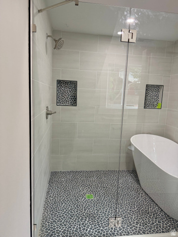 8965 Quail Run Drive Sandy, UT 84093 - Photo 47 of 56 Glass-enclosed shower featuring a pebble-stone floor, light-toned rectangular wall tiles, and built-in shower niches