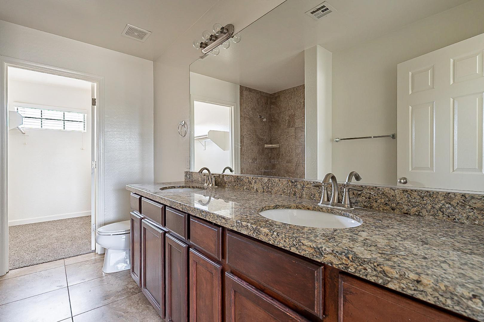 17223 North Cave Creek Road, Unit 7 Phoenix, AZ 85032 - Photo 20 of 23 a bathroom with a granite countertop sink a toilet and a mirror