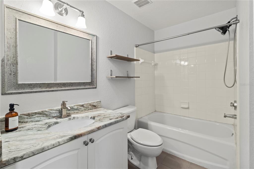 8827 Manor Loop, Unit 201 Lakewood Ranch, FL 34202 - Photo 21 of 39 a bathroom with a granite countertop sink a toilet and shower