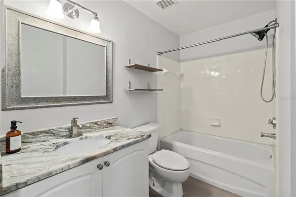 a bathroom with a granite countertop sink a toilet and shower