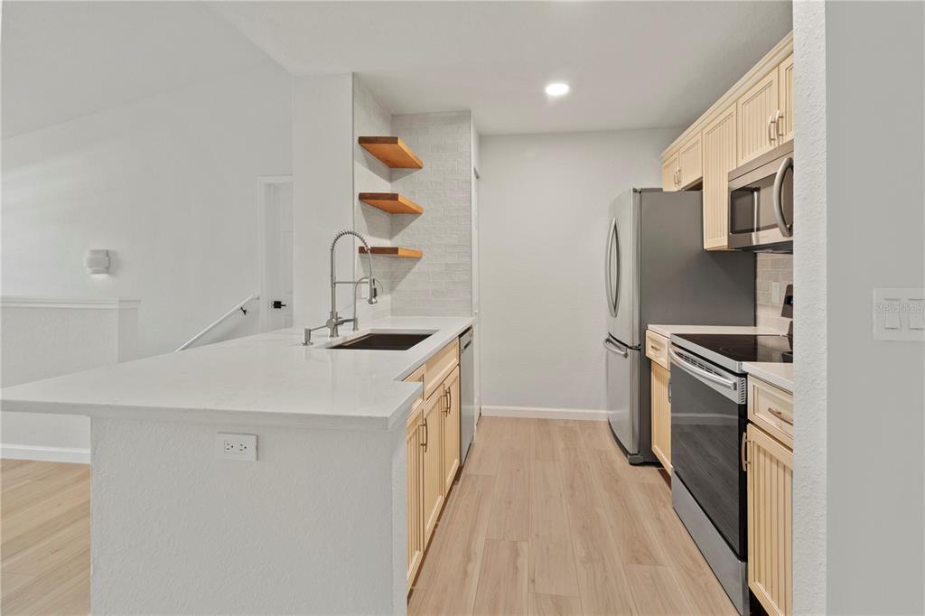 8827 Manor Loop, Unit 201 Lakewood Ranch, FL 34202 - Photo 26 of 39 a kitchen with stainless steel appliances a sink dishwasher a refrigerator and a stove with wooden floor