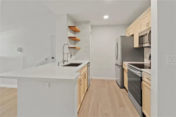 a kitchen with stainless steel appliances a sink dishwasher a refrigerator and a stove with wooden floor