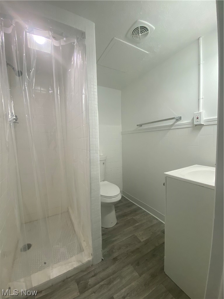 12913 Silver Road Cleveland, OH 44125 - Photo 20 of 23 Basement Bathroom with new floors, mirror, vanity, a shower with shower curtain, and tile walls