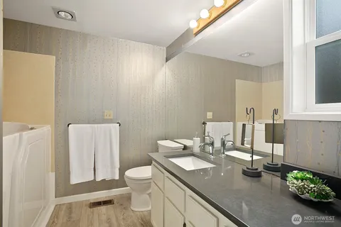 a bathroom with a granite countertop sink a toilet and a mirror