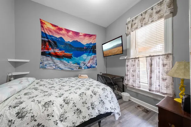 a bedroom with a bed a dresser next to a window