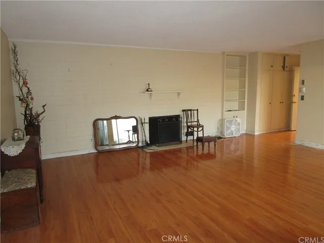a view of empty room with wooden floor and furniture