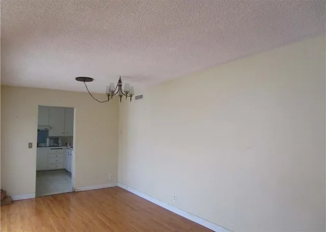a view of empty room with wooden floor and kitchen