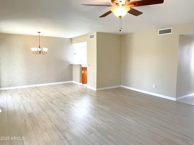 an empty room with wooden floor ceiling fan and window