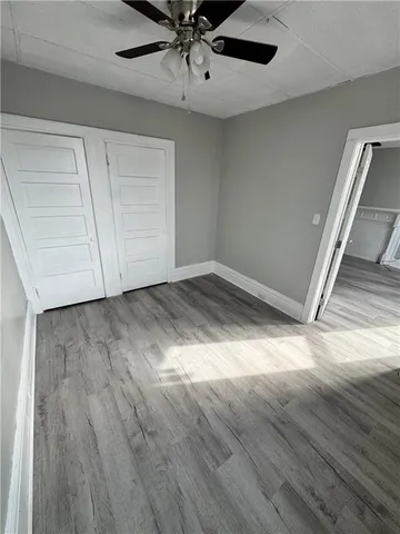 an empty room with wooden floor fan and windows