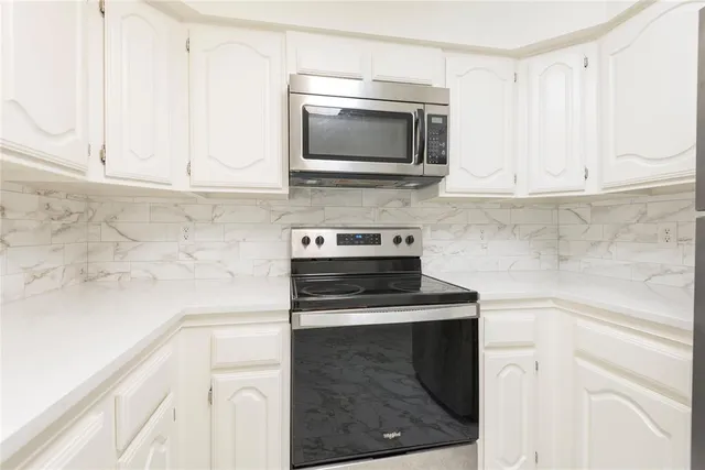 a kitchen with granite countertop white cabinets and stainless steel appliances
