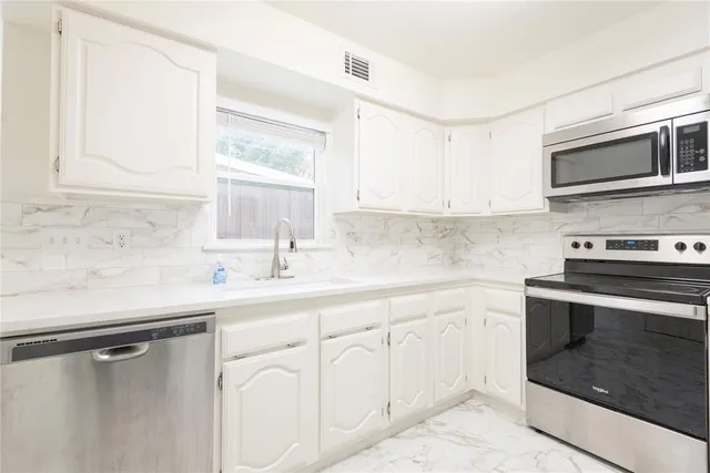 a kitchen with white cabinets sink and stainless steel appliances
