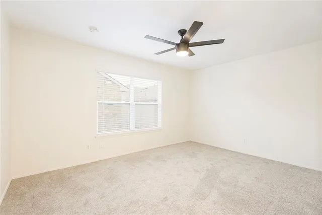 an empty room with a window and a fan