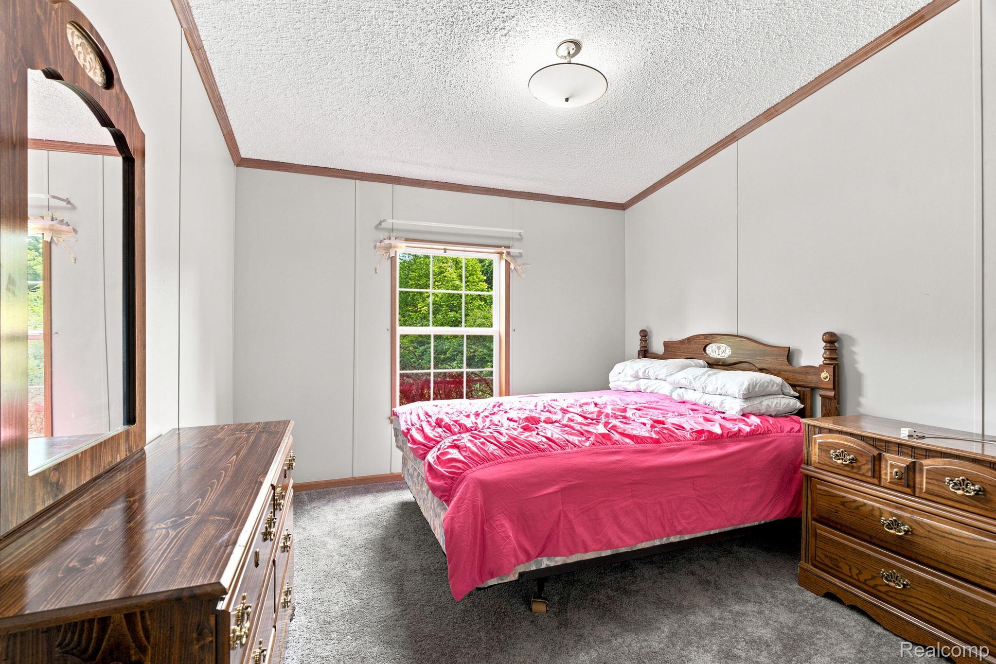 2390 Lakeshore Road Applegate, MI 48401 - Photo 27 of 97 Bright secondary bedroom featuring wood-frame bed, wood-finish dresser with carved details, hardwood flooring, and large multi-pane window with natural light
